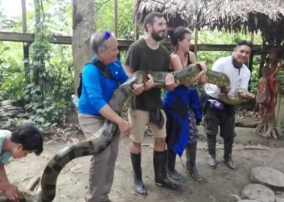 Group of travelers holding an anaconda in the Amazon